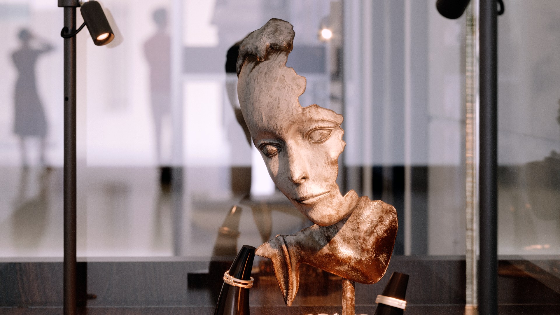 Dois postes EVIDENZA iluminando uma escultura e joias dentro de uma vitrine